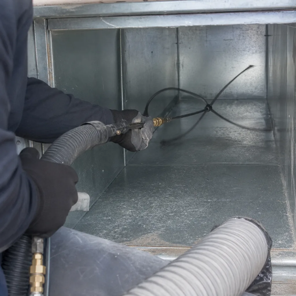 Technician using professional tools to clean metallic home air duct system